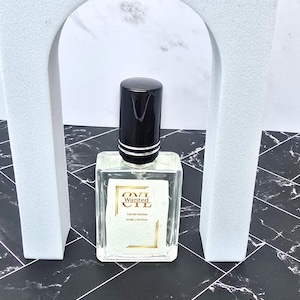 May include: A white ceramic mug with a black handle and the text "But First, Coffee" in a handwritten style. The mug is on a white surface. The mug is approximately 4 inches tall.