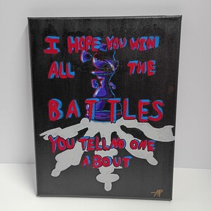 May include: A black canvas art piece with the text "I HOPE YOU WIN ALL THE BATTLES YOU TELL NO ONE ABOUT" in red and blue. A purple and blue chess piece is in the center, with a silver and white design below.