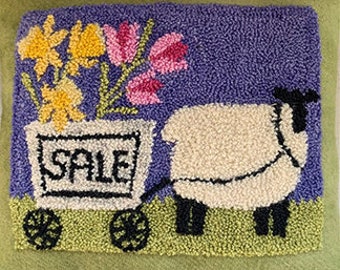 May include: A white sheep pulling a wagon with flowers and the word "SALE" on the side. The wagon has black wheels and a green base. The background is a purple and green field.