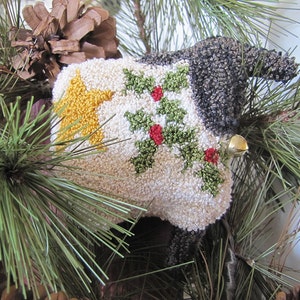 May include: A white, gray, and green Christmas ornament shaped like a reindeer with a gold star and holly accents.