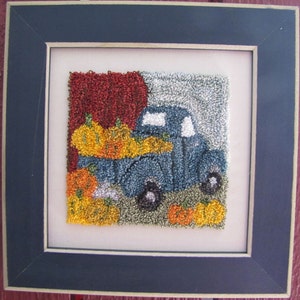 May include: A blue pickup truck with a white cab and a bed full of orange pumpkins. The truck is on a green and brown background with a red and white background behind it.