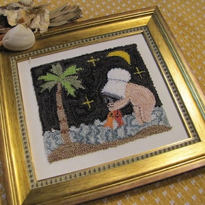 May include: A framed needlepoint artwork depicting a person in a white hat standing on a beach at night. The person is holding a small orange object. A palm tree is in the background. The artwork is framed in a gold frame.