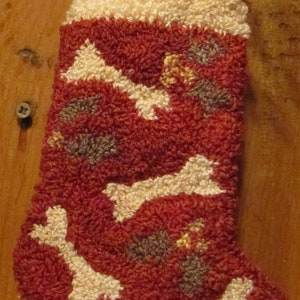 May include: A red and white Christmas stocking with a bone pattern. The stocking is filled with green sprigs.