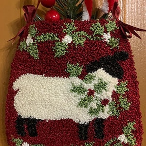 May include: A red felt stocking with a white sheep and green holly design. The stocking is decorated with a candy cane and red berries.