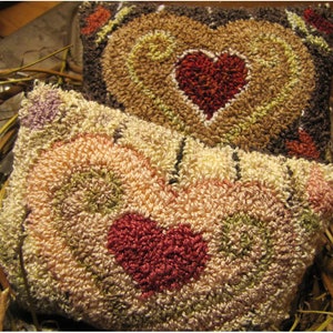 May include: Two handmade heart-shaped pillows with a brown, cream, and red color scheme. The pillows are made with a fluffy, textured fabric and feature a heart design in the center.