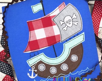 May include: A blue applique design of a pirate ship with a red and white checkered sail, a skull and crossbones flag, and an anchor. The ship is on a blue background with white waves.