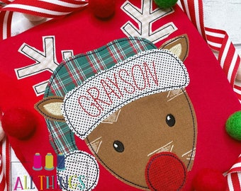 May include: Red applique shirt with a reindeer wearing a plaid hat with the name Grayson embroidered on it. The reindeer has a red nose and brown antlers.