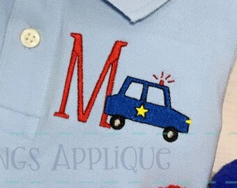 May include: A light blue polo shirt with a red embroidered letter "M" and a blue and yellow embroidered police car with a red flashing light. The text "All Things Applique" is embroidered below the design.