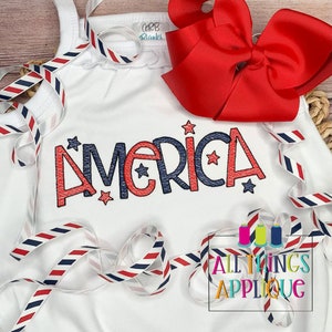 May include: White sleeveless shirt with a red, white, and blue "America" applique with stars. The shirt is decorated with red, white, and blue striped ribbon.