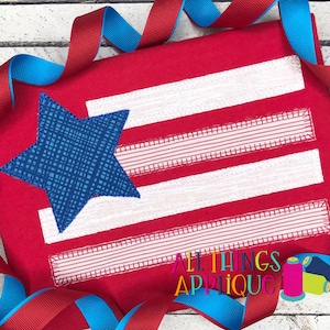 May include: Red fabric with a white and blue applique of a star and stripes. The fabric has the text "All Things Applique" in white.