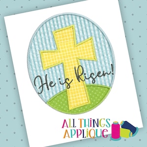 May include: A yellow cross with a blue and white striped background and green grass. The text "He is Risen!" is written in black cursive.