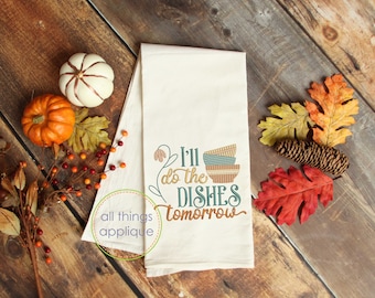 May include: A white tea towel with the text "I'll do the dishes tomorrow" embroidered in green, brown, and blue. The text is surrounded by a green vine with a brown flower. There are three stacked bowls in the design, with brown, blue, and white stripes. The text "all things applique" is in a circle on the towel.