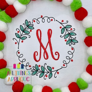 May include: Embroidered Christmas wreath with green leaves and red berries, featuring the letter "M" in the center. The wreath is surrounded by a white background.
