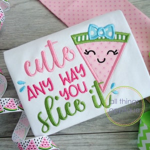 May include: A white t-shirt with green and pink embroidery that says "cute any way you slice it". A pink watermelon slice with a green rind and a blue bow is embroidered above the text.