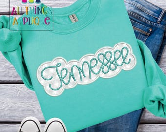 May include: A turquoise sweatshirt with a white and silver embroidered design that says "Tennessee".