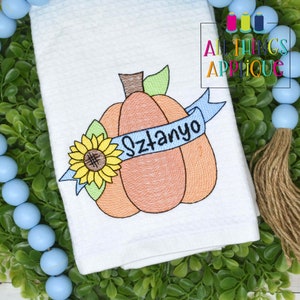 May include: Embroidered white kitchen towel with a pumpkin, sunflower, and blue ribbon with the name "Szatanyo" on it.