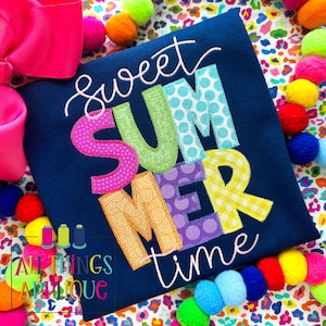 May include: A navy blue t-shirt with the text "Sweet Summer Time" in colorful, patterned letters. The letters are stitched with different patterns, including polka dots, gingham, and swirls.