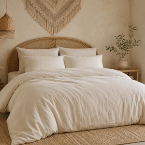 May include: A cream-coloured bed set with a woven headboard and pillows. The bedding includes a duvet cover and pillowcases. The room is decorated with natural elements, including a woven wall hanging, a woven rug, and dried plants in a vase.