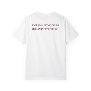 Może przedstawiać: Biały t-shirt z krótkim rękawem z napisem "I'M PROBABLY GOING TO HELL IN EVERY RELIGION." nadrukowanym ciemnoczerwonymi wielkimi literami na wysokości klatki piersiowej. Odzież posiada standardowy okrągły dekolt oraz gładki tył bez żadnych wzorów.