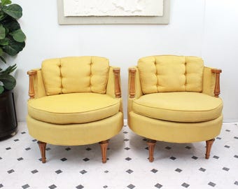 May include: Two yellow swivel chairs with wooden legs and arms. The chairs are upholstered in a yellow fabric with button tufting.