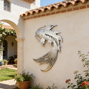 Könnte beinhalten: Eine große Wandskulptur aus silberfarbenem Metall, die einen Koi-Fisch darstellt und an einer cremefarbenen Stuckwand befestigt ist. Die Skulptur hat detaillierte Schuppen und fließende Flossen und verleiht dem Außenbereich einen Hauch von naturnaher Kunst. Die Skulptur ist etwa 120 cm lang.