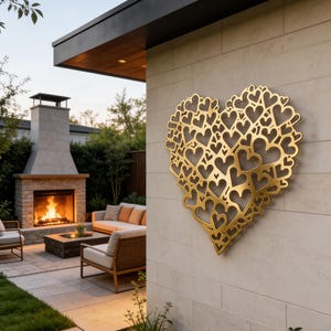 Pode incluir: Uma obra de arte de parede em forma de coração de metal dourado, composta por inúmeros recortes em forma de coração. A obra está montada numa parede de pedra clara, com um pátio exterior e uma lareira ao fundo.