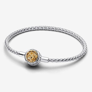 May include: A silver chain bracelet featuring a round clasp with a gold-toned dragon motif. The clasp is engraved with the text FIRE & BLOOD. The bracelet has a textured, woven-style silver chain design that connects to the central circular clasp.