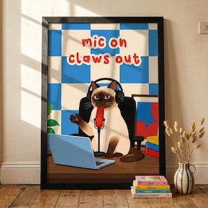 May include: Framed art print depicting a cartoon Siamese cat with headphones and a microphone, with the text "mic on claws out". The cat is at a desk with a laptop. The background is a blue and white chequered pattern.