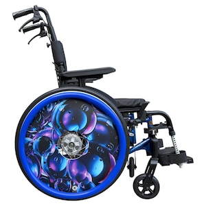 May include: A blue and black wheelchair with a distinctive design. The wheels have a vibrant blue rim and a colourful bubble pattern. The wheelchair has a black seat, armrests, and handles, with a robust frame.