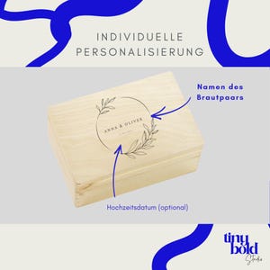 K&ouml;nnte beinhalten: Eine rechteckige, helle Holzschatulle mit einer Lasergravur auf dem Deckel. Das Design zeigt einen kreisf&ouml;rmigen Blattkranz, der den Text ANNA & OLIVER sowie ein Datum umschlie&szlig;t. Blaue Pfeile zeigen auf den Text und das Datum.