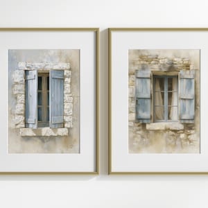 Puede incluir: Dos impresiones artísticas enmarcadas con pinturas de acuarela de ventanas con contraventanas azules. Las ventanas están en muros de piedra envejecida, con marcos dorados. La obra evoca una estética europea rústica.