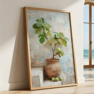 May include: A framed art print depicts a fig tree in a terracotta pot. The artwork features green leaves and figs, set against a textured, muted background. The frame is a light wood color, and the overall aesthetic is natural and serene.
