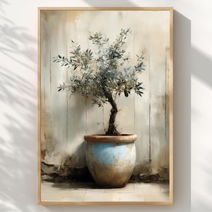 May include: A framed art print depicting an olive tree in a blue and brown ceramic pot. The tree has green and grey leaves and a dark brown trunk. The background is a light beige and brown, with a wooden frame.
