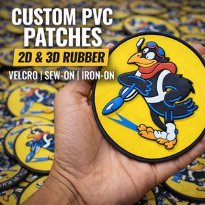 May include: A yellow, black, and blue custom PVC patch featuring a cartoon bird in a pilot's cap and scarf, holding a blue missile. The patch has the text "CUSTOM PVC PATCHES 2D & 3D RUBBER VELCRO | SEW-ON | IRON-ON".