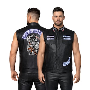 Op de afbeelding: Zwarte leren vest met meerdere patches. De voorkant heeft twee borstzakken en patches met de tekst "V President", "Redwood Original" en "SAMCRO". De achterkant toont een grote patch met een zeis en de woorden "Sons of Anarchy".