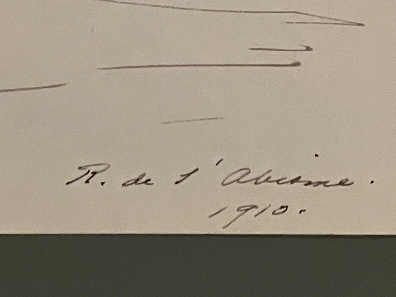 May include: A sketch on off-white paper with handwritten text. The text includes the name "R. de l'Ab&icirc;me" and the year "1910". The sketch features faint lines, possibly depicting a landscape or abstract shapes.