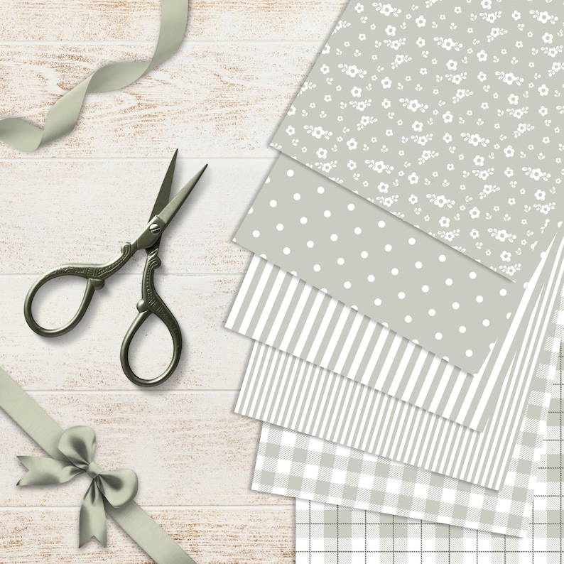 May include: A collection of patterned paper sheets in gray and white, featuring floral, polka dot, striped, and gingham designs. A pair of vintage scissors and a gray ribbon with a bow are also present, all arranged on a light wood surface.
