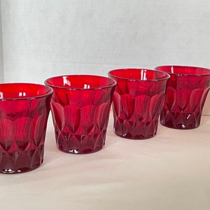 May include: Set of four red glass tumblers with a diamond pattern. The tumblers are clear and have a deep red color.
