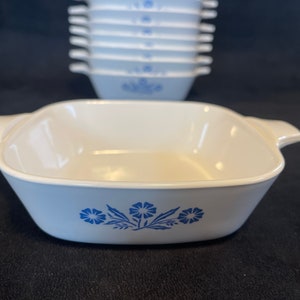 May include: A stack of light blue and white square casserole dishes with handles. The front dish has a blue floral design. Additional dishes are stacked in the background.