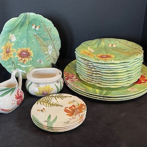 May include: A set of green and white floral patterned ceramic dinnerware, including a large platter, a smaller platter, a creamer, a sugar bowl, and four salad plates.
