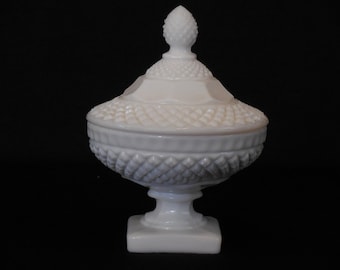 May include: A white milk glass candy dish with a lid. The dish has a diamond pattern and a pedestal base. The lid has a pineapple finial.