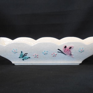 May include: White ceramic planter with a scalloped edge and a design of butterflies and flowers.