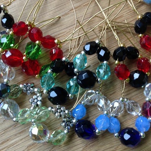 May include: A collection of handmade beaded ornaments in various colours, including red, green, black, blue, and clear. The ornaments are made with small glass beads and are strung on wire.