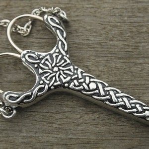 May include: A silver pendant necklace featuring a detailed design of a pair of scissors with a Celtic knot pattern. The pendant is attached to a silver chain.