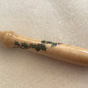 May include: A wooden tool handle with a holly and berry design painted on it.