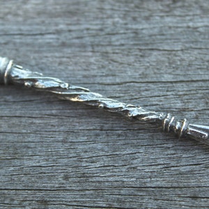 May include: A silver, twisted metal wand with a loop at the end. The wand is about 6 inches long.