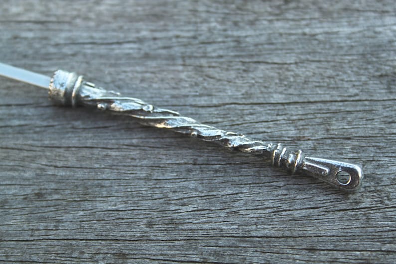 May include: A silver, twisted metal wand with a loop at the end. The wand is about 6 inches long.
