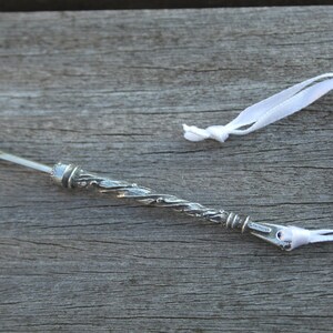 May include: A silver thimble with a decorative design and a white ribbon attached to it.