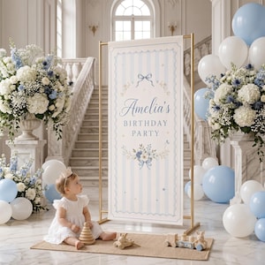Puede incluir: Una pancarta rectangular vertical para fiesta de cumpleaños con rayas azul claro, que presenta el texto Amelia's BIRTHDAY PARTY, decorada con lazos azules e ilustraciones florales, exhibida en un soporte de metal dorado con globos blancos y azules.
