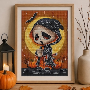 Könnte beinhalten: Ein gerahmtes Kreuzstichbild mit einer stilisierten Figur in einem schwarzen Kapuzenumhang, die eine Tasse hält. Der Hintergrund zeigt einen großen gelben Mond, einen orangefarbenen Himmel, fallenden Regen, zwei Kürbisse und eine fliegende Fledermaus.